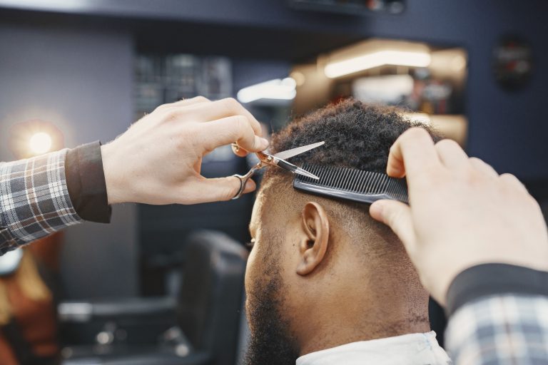 Coiffeur coupant des cheveux afro au ciseau et au peigne en salon