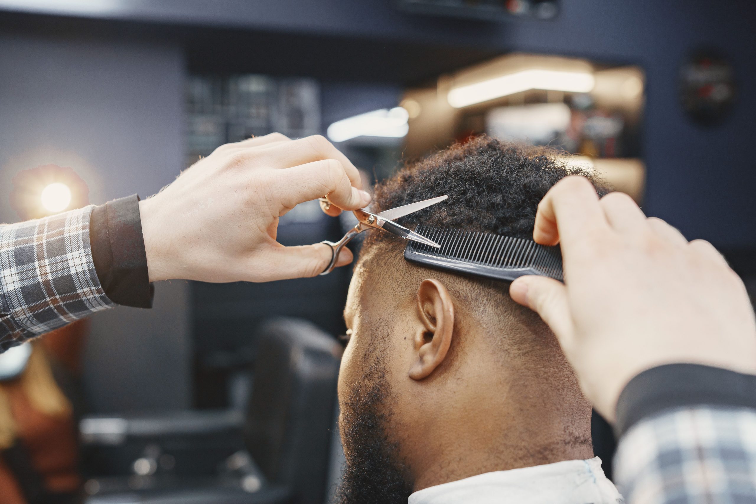 Coiffeur coupant des cheveux afro au ciseau et au peigne en salon