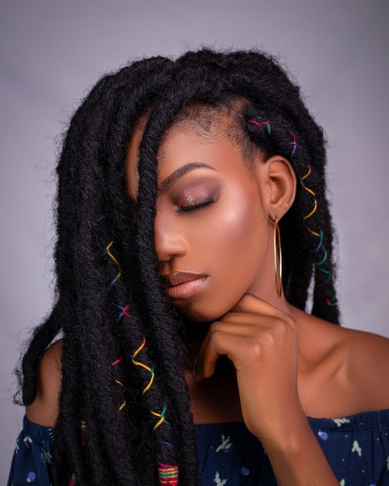 Femme aux longues fausses locks ornées de fils colorés, coiffure protectrice afro