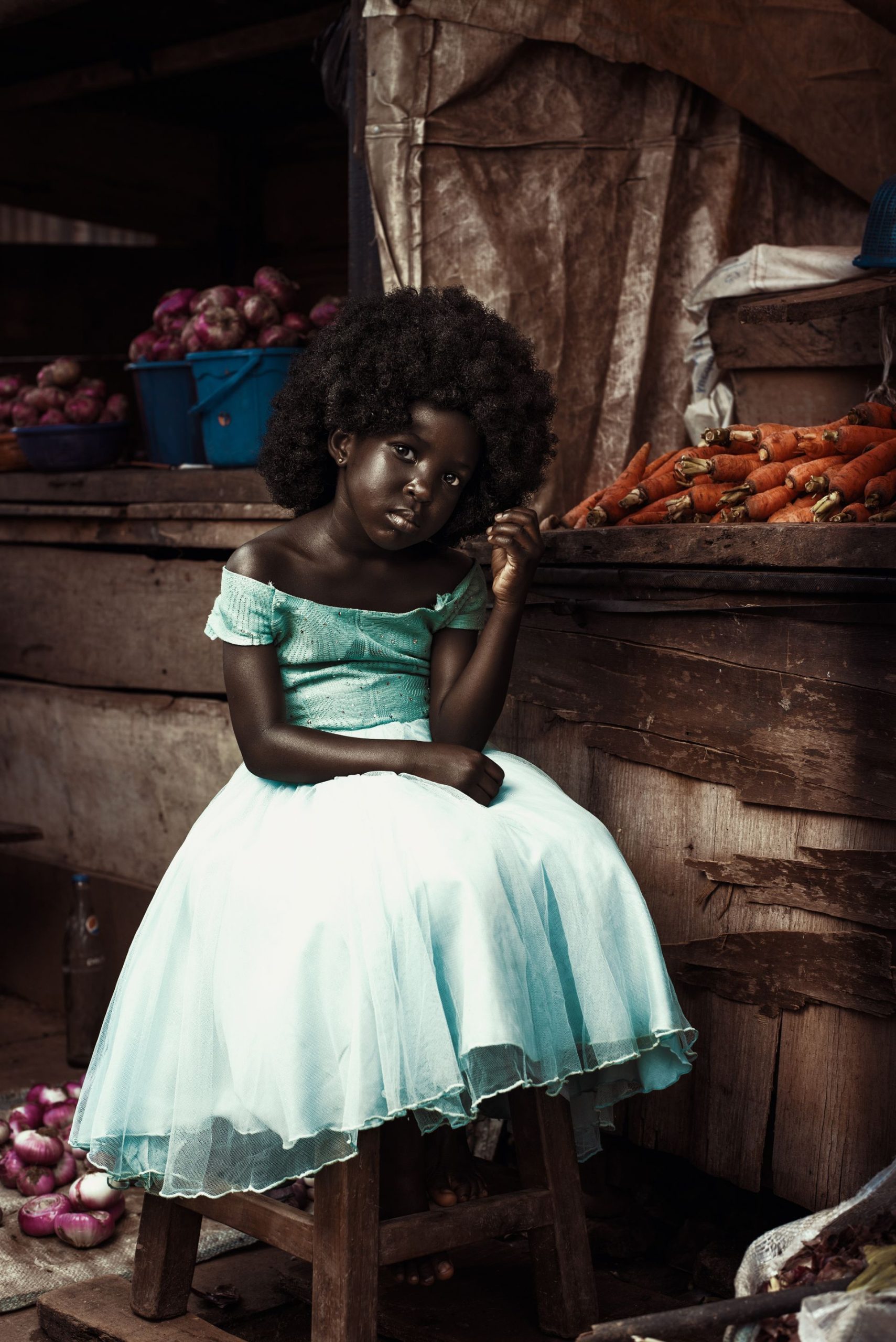 Petite fille aux cheveux afro dans un marché entouré d oignons et de légumes